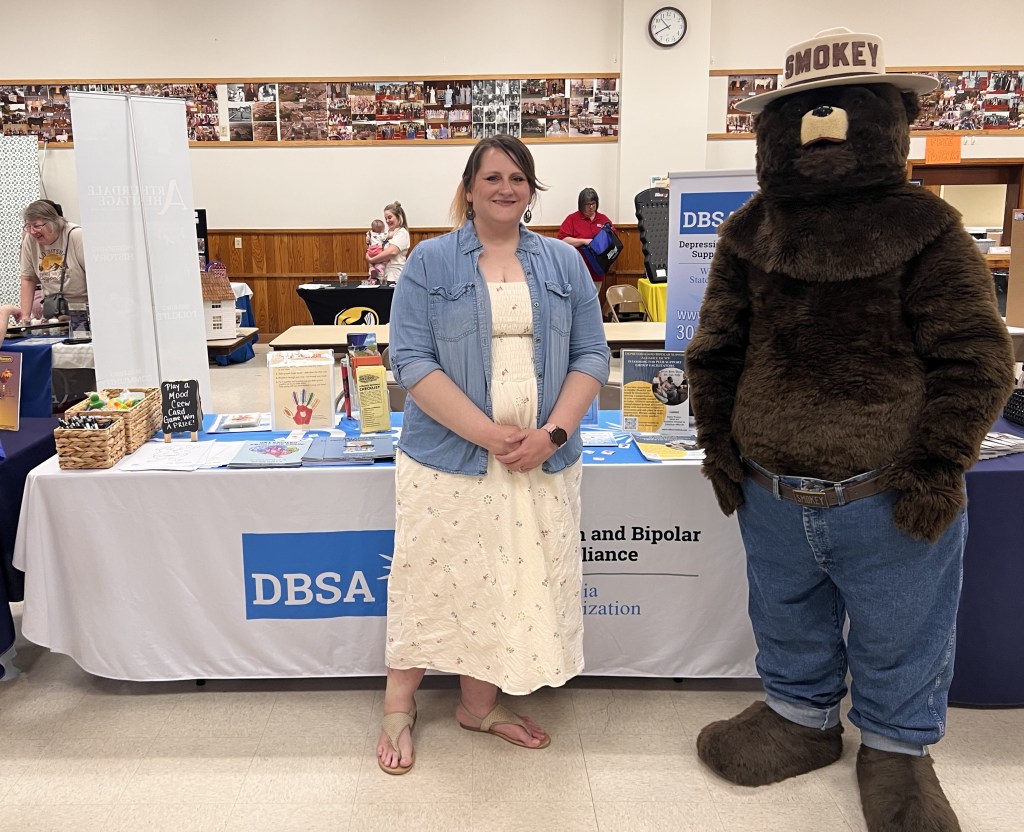 Smokey the Bear and Stacie Weaver stand in front of the DBSA WV table